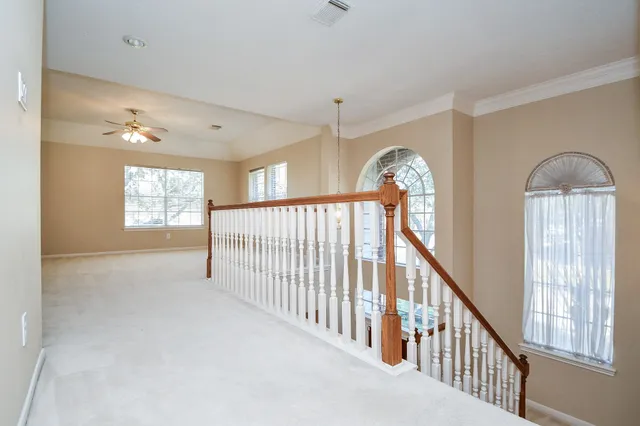 an empty room with a chandelier fan and windows
