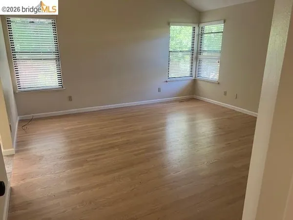 an empty room with wooden floor and windows