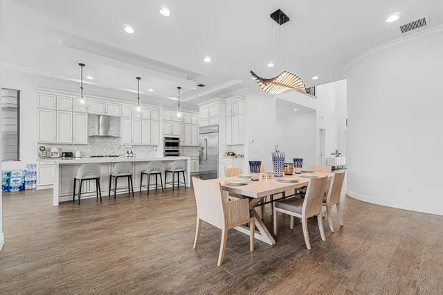 a kitchen with stainless steel appliances granite countertop a table chairs stove and refrigerator