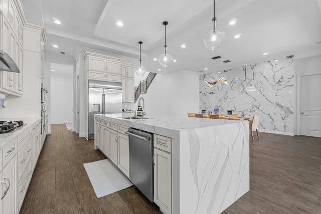 a kitchen with stainless steel appliances kitchen island granite countertop a table chairs sink and cabinets