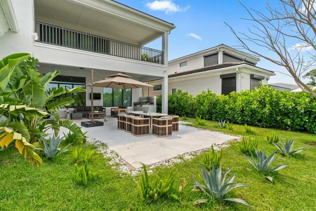a view of a patio with couches table and chairs under an umbrella