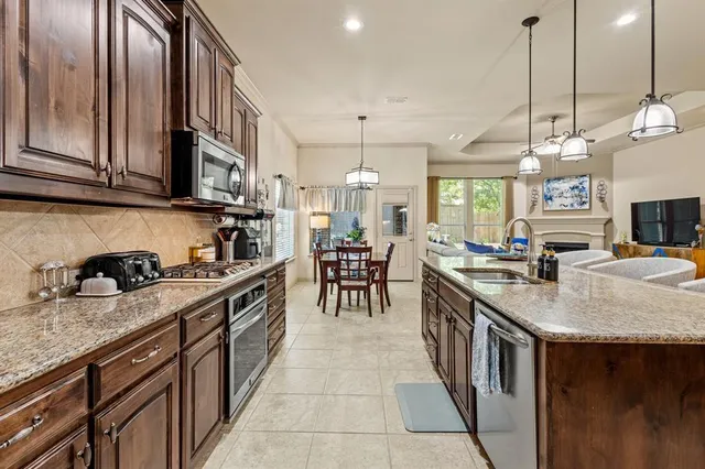 a kitchen with stainless steel appliances granite countertop a sink a stove and a wooden cabinets