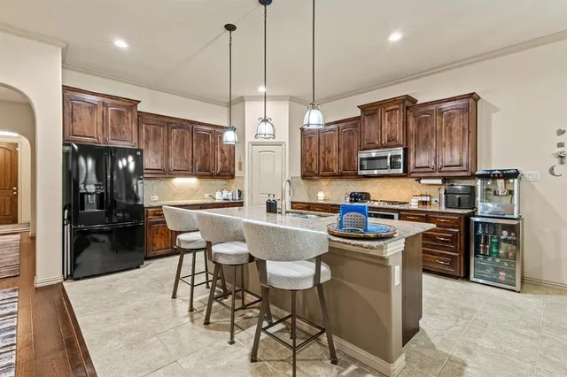 a kitchen with stainless steel appliances granite countertop a stove top oven a refrigerator a sink and a chairs