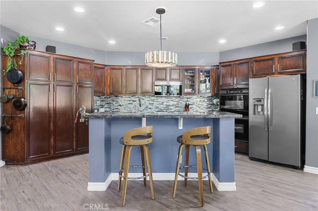 12786 North Rim Way Rancho Cucamonga, CA 91739 - Photo 15 of 50 a kitchen with stainless steel appliances kitchen island granite countertop a refrigerator a stove a oven a dining table and chairs with wooden floor