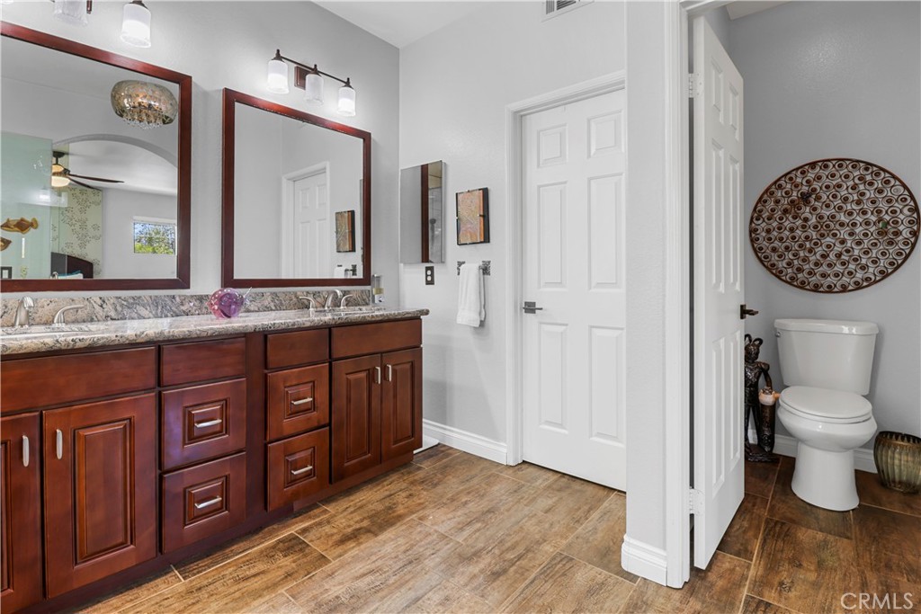 12786 North Rim Way Rancho Cucamonga, CA 91739 - Photo 29 of 50 a bathroom with a granite countertop sink a toilet and a mirror