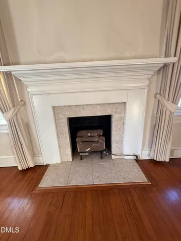 an empty room with wooden floor and fireplace