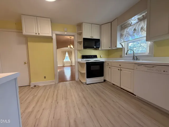 a kitchen with stainless steel appliances granite countertop a stove a sink dishwasher and a refrigerator with wooden floor