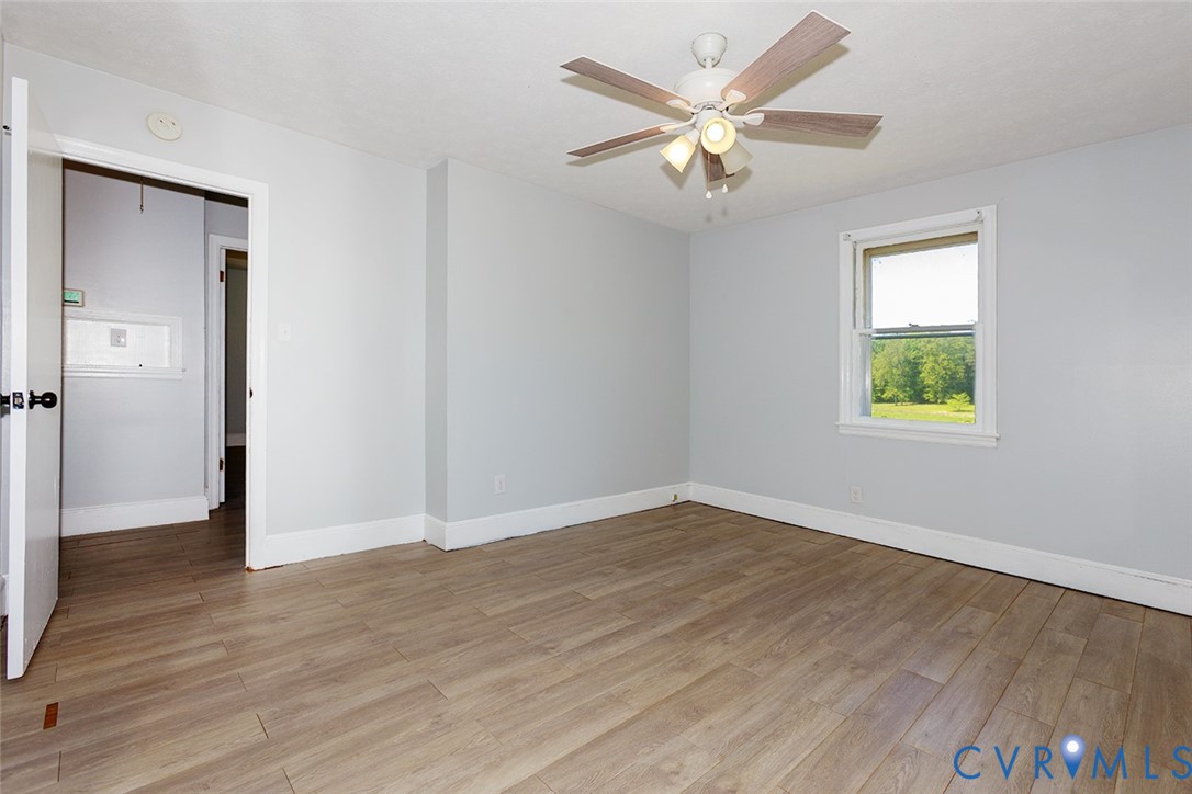 9903 Boze Road Ford, VA 23850 - Photo 20 of 45 an empty room with wooden floor chandelier fan and windows