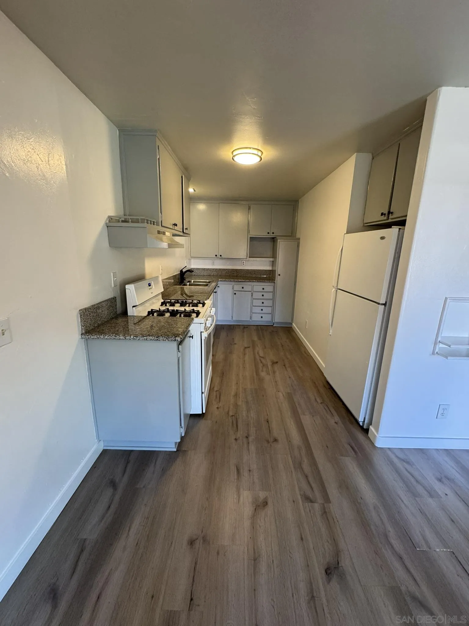 a kitchen with wooden floors and white appliances