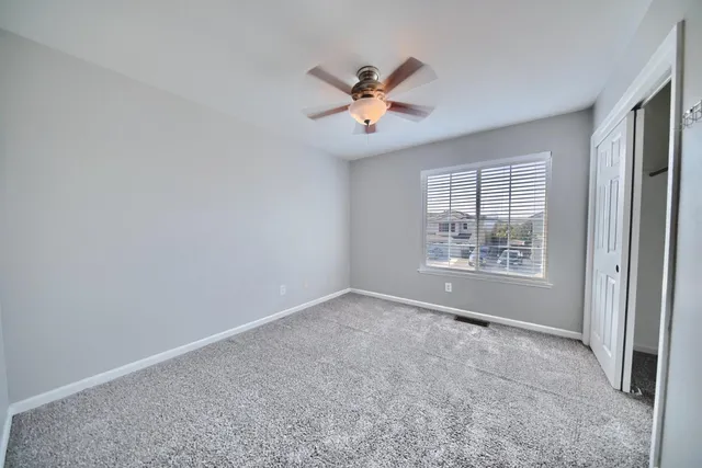 an empty room with windows and fan