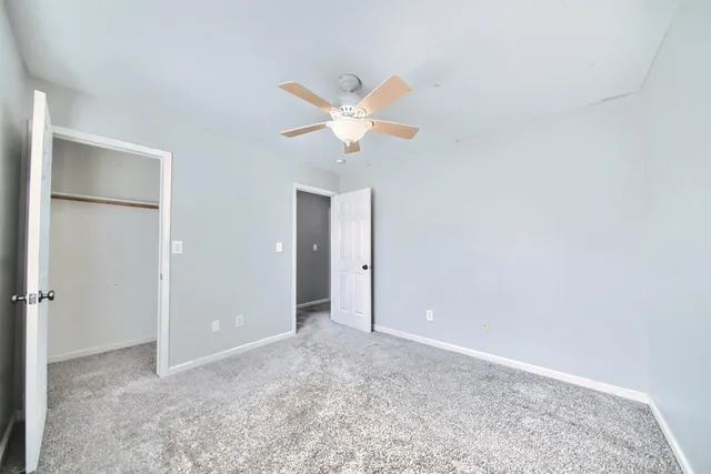 an empty room with closet and a chandelier fan