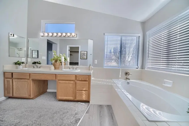 a spacious bathroom with a tub a double vanity sink a window and a mirror