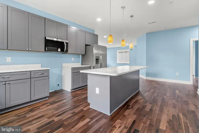 a kitchen with a sink wooden floor and black appliances