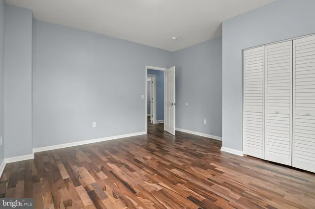a view of an empty room with wooden floor and closet