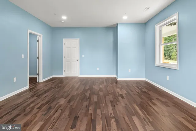 a view of an empty room and window and wooden floor
