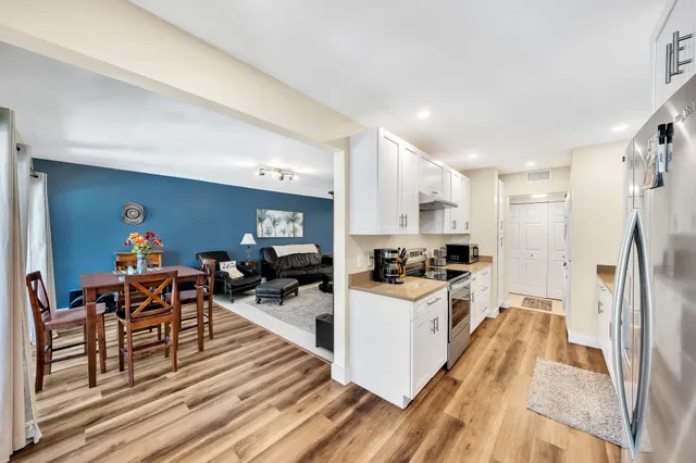 a kitchen with stainless steel appliances a stove a sink a refrigerator cabinets and dining table