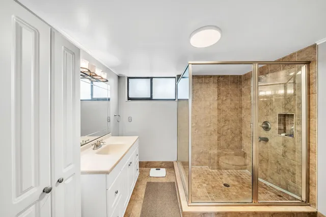 a bathroom with a granite countertop sink a mirror and a shower