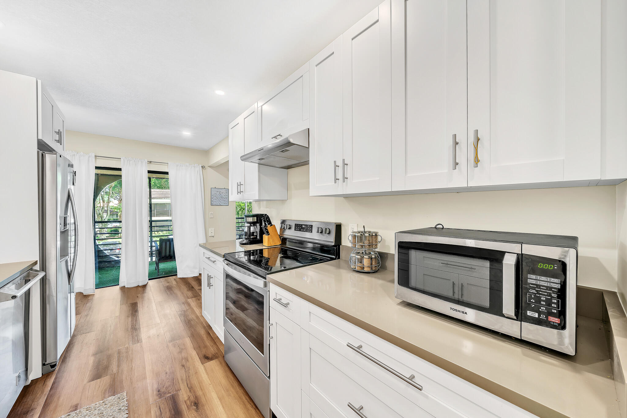 6342 Longboat Lane West, Unit 201 Boca Raton, FL 33433 - Photo 5 of 40 a kitchen with stainless steel appliances a stove microwave and cabinets