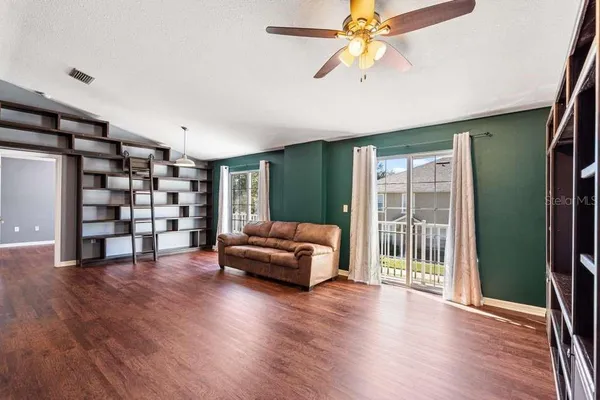 a view of an empty room with a window and wooden floor
