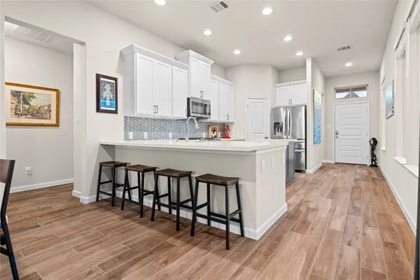 a kitchen with stainless steel appliances a dining table chairs microwave and sink