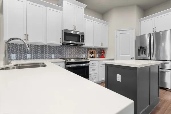 a kitchen with stainless steel appliances a white stove top oven a sink a refrigerator and white cabinets