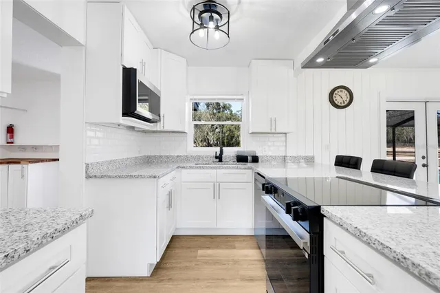 a kitchen with kitchen island granite countertop a sink a counter space appliances and cabinets