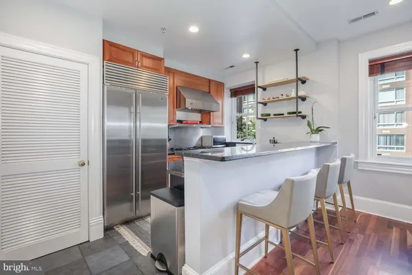 a kitchen with kitchen island white cabinets a refrigerator and a dining table
