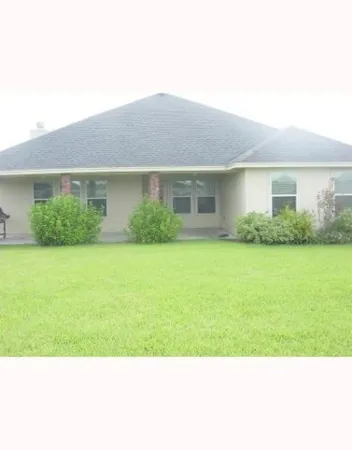 a view of house in front of a big yard with potted plants