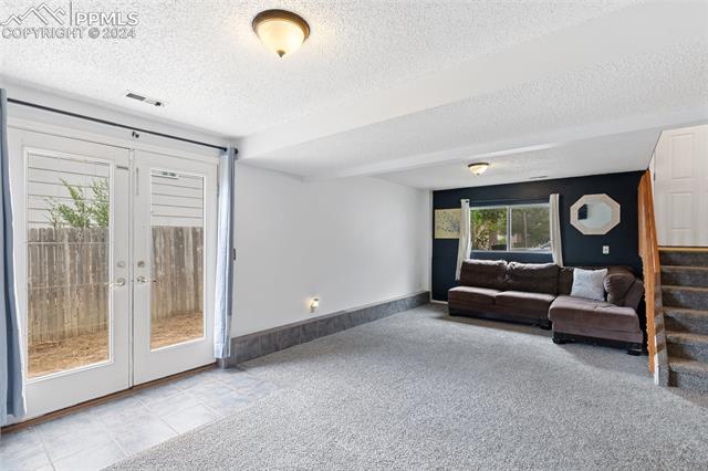 604 Wheat Field Road Fountain, CO 80817 - Photo 19 of 33 Living room featuring light carpet, french doors, and a textured ceiling
