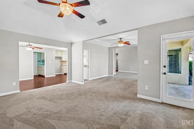 an empty room with ceiling fan and windows