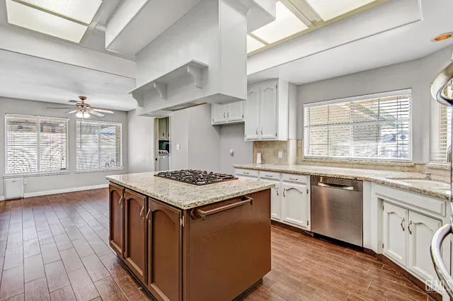 a kitchen with stainless steel appliances granite countertop wooden floor sink stove and wooden cabinets