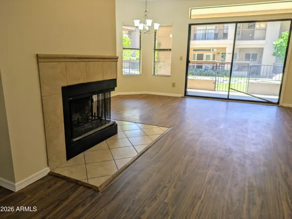 an empty room with wooden floor fireplace and windows