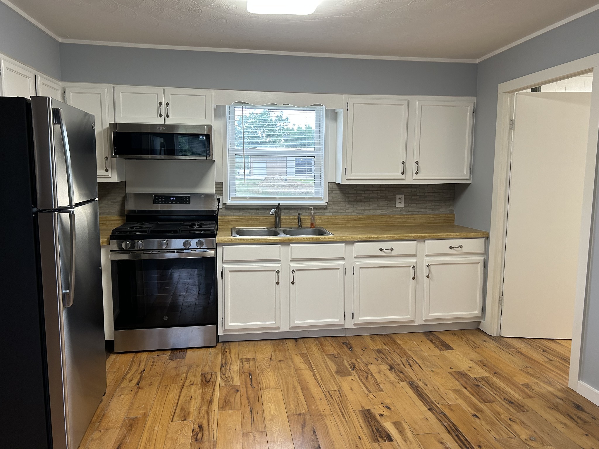 20 Ball Park Road Big Sandy, TN 38221 - Photo 17 of 33 a kitchen with granite countertop a refrigerator stove and white cabinets