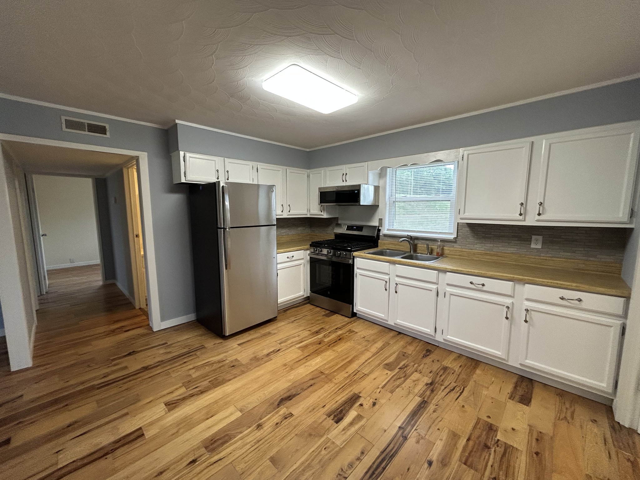 20 Ball Park Road Big Sandy, TN 38221 - Photo 28 of 33 a kitchen with granite countertop a refrigerator oven a sink dishwasher and white cabinets with wooden floor