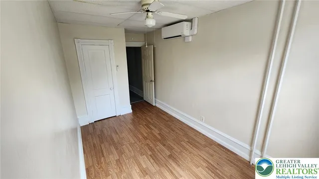 an empty room with wooden floor and a ceiling fan