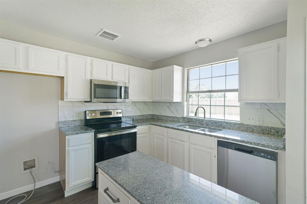 1019 Danforth Court Arlington, TX 76017 - Photo 16 of 37 a kitchen with granite countertop white cabinets sink and stainless steel appliances