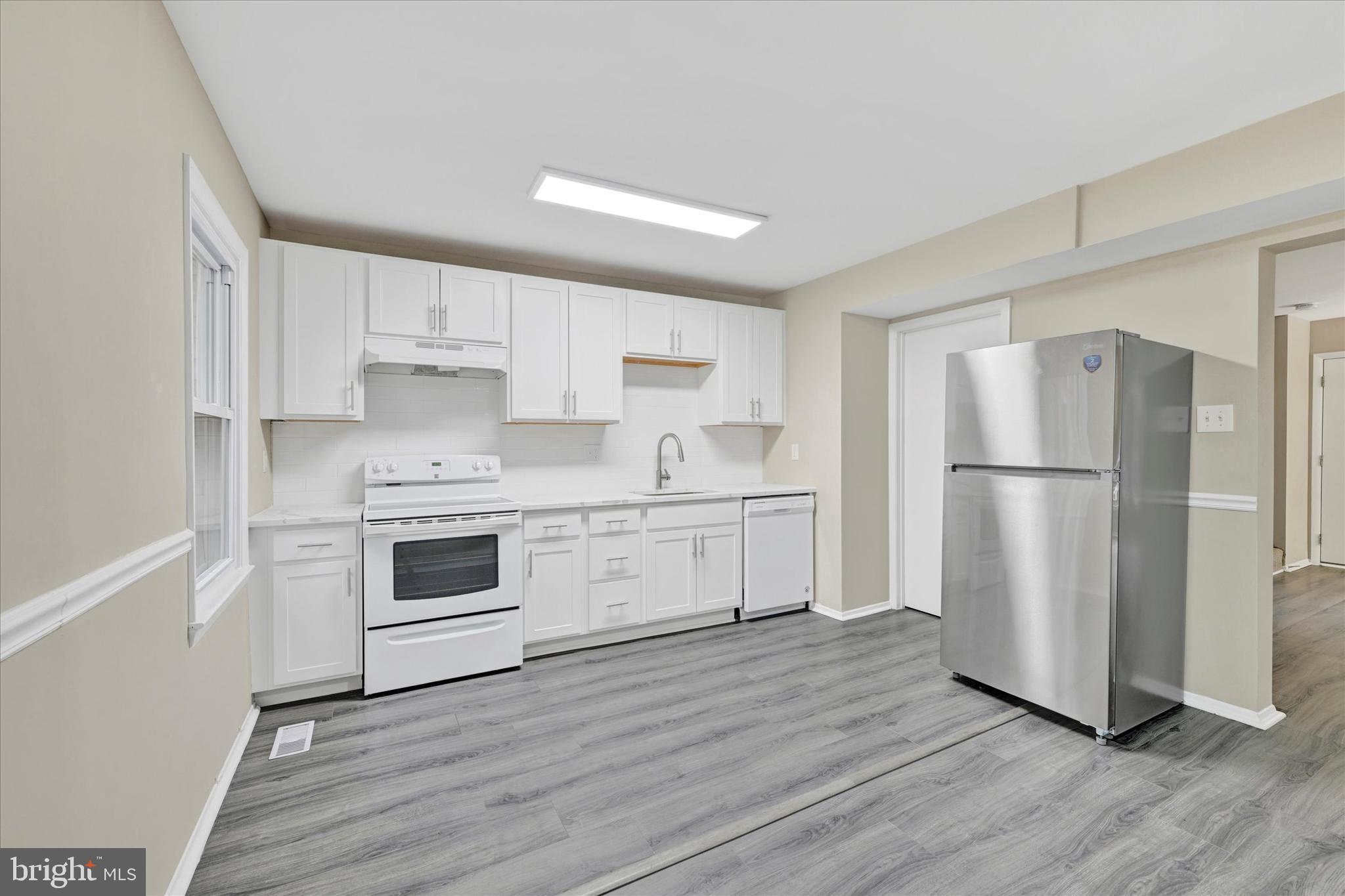 3447 Santee Road Baltimore, MD 21236 - Photo 11 of 32 a kitchen with white cabinets white appliances and sink