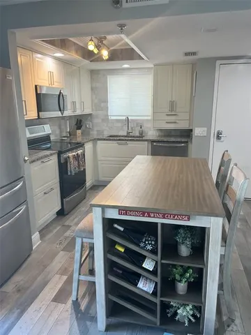 a kitchen with kitchen island a counter space a sink appliances and cabinets