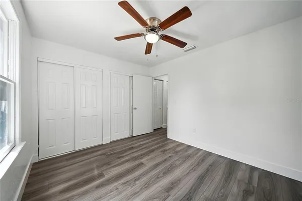 an empty room with wooden floor and ceiling fan