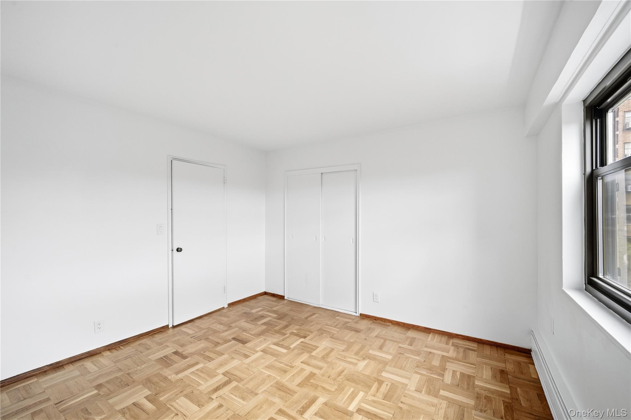 21-41 34th Avenue, Unit 7B Queens, NY 11106 - Photo 9 of 14 Unfurnished bedroom featuring a baseboard radiator and a closet