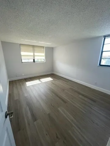 an empty room with wooden floor cabinet and windows