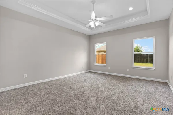 an empty room with windows and ceiling fan