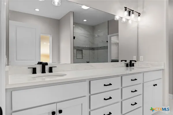 a bathroom with double vanity sinks and a shower