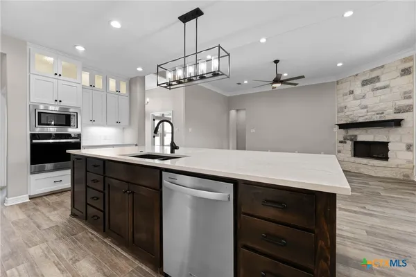 a kitchen with kitchen island a center island wooden floor stainless steel appliances and cabinets
