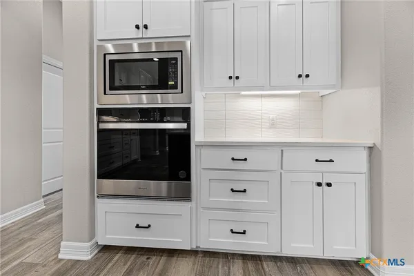 a kitchen with white cabinets and oven