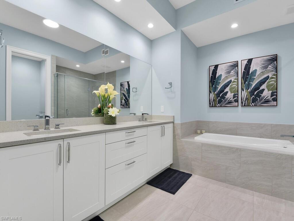 1111 Central Avenue, Unit 216 Naples, FL 34102 - Photo 17 of 50 a bathroom with a double vanity sink a large mirror a bathtub and a shower