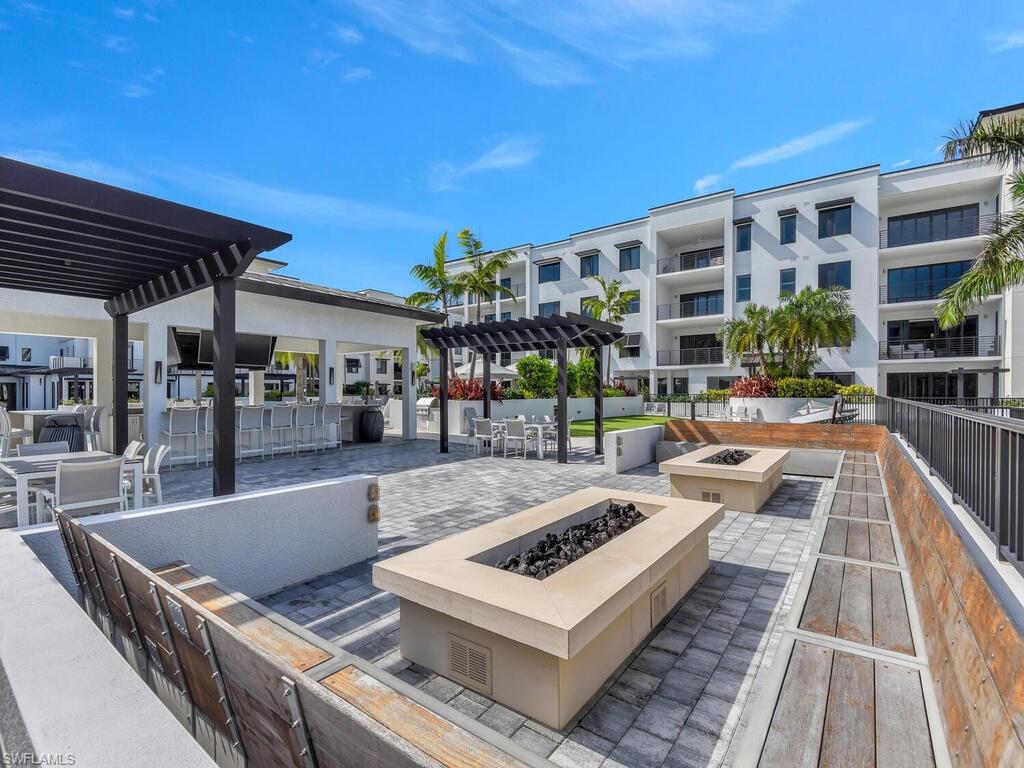 1111 Central Avenue, Unit 216 Naples, FL 34102 - Photo 44 of 50 a view of a patio with dining table and chairs with wooden floor and fence