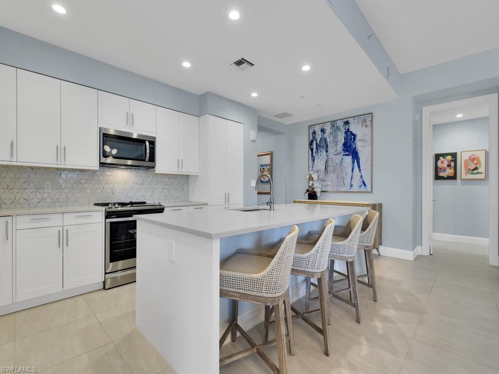 1111 Central Avenue, Unit 216 Naples, FL 34102 - Photo 7 of 50 a kitchen with stainless steel appliances a stove a sink a white table and chairs