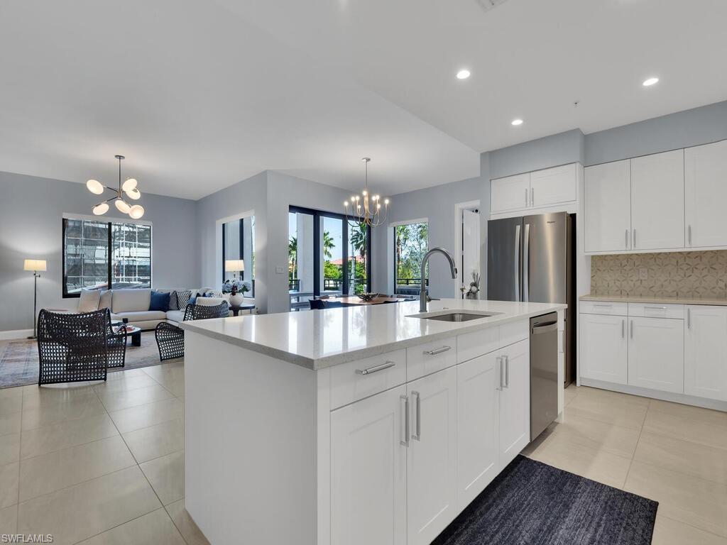1111 Central Avenue, Unit 216 Naples, FL 34102 - Photo 8 of 50 a large kitchen with kitchen island white cabinets and stainless steel appliances