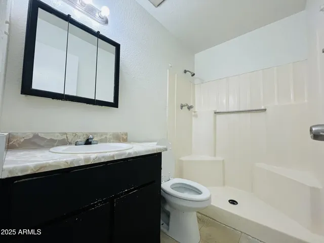 a bathroom with a granite countertop sink toilet a mirror and shower